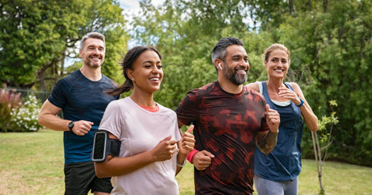 a middle-aged man running in the park with his kids