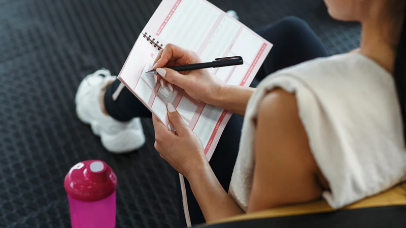 woman writing a weekly workout schedule