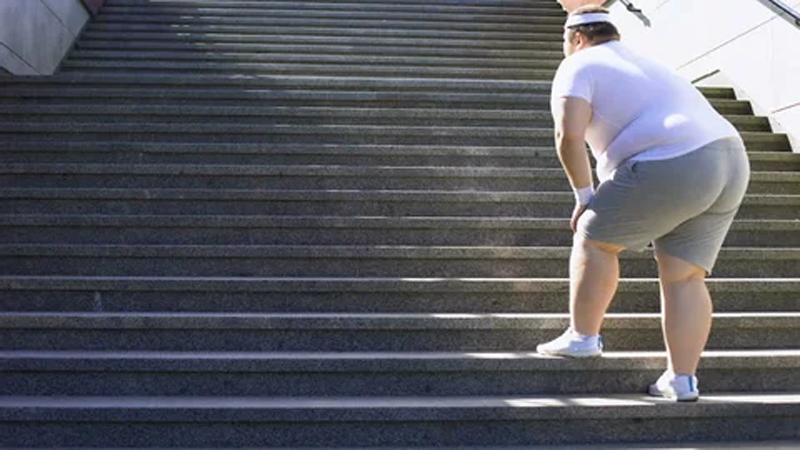 a man carrying excessive weight, climbing stairs