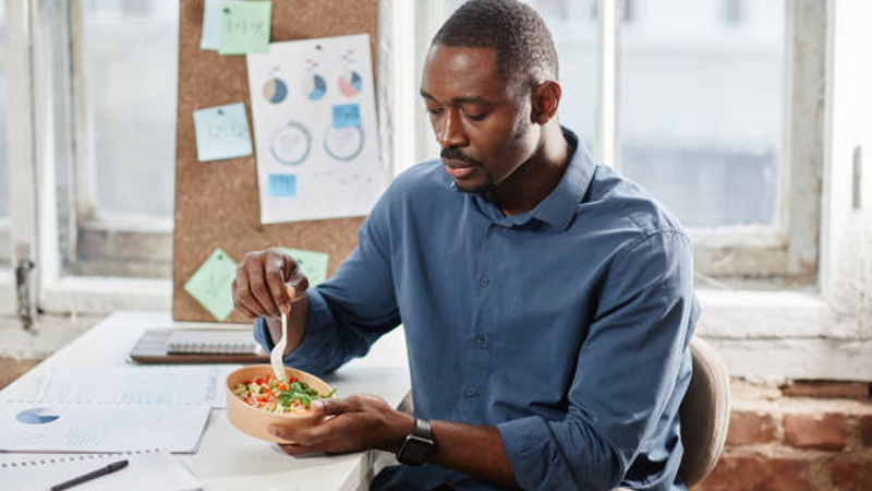 a man eating homemade lunch at his office desk